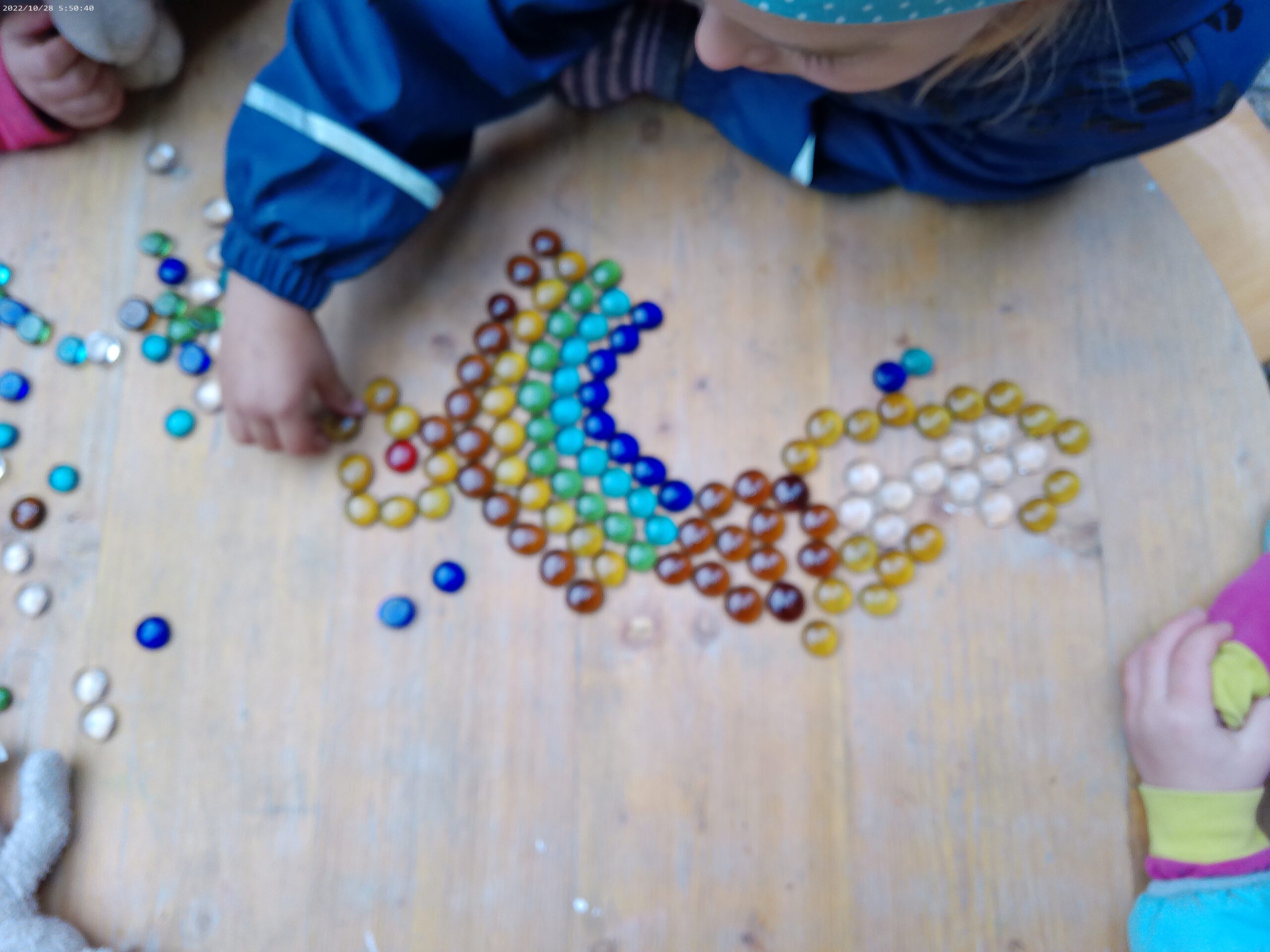 Ein Kind legt einen Regenbogen aus Muggelsteinen